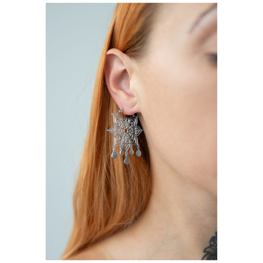 Pendientes Mandala plateados usados, enfocados en la oreja, cabello rubio