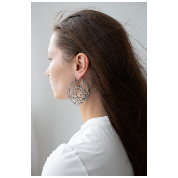 Aros Lotus plateados en mujer con cabello largo y camisa blanca