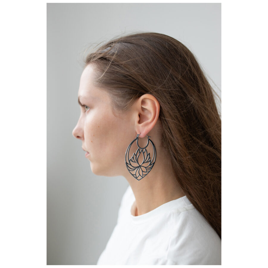 Mujer con cabello largo lleva grandes pendientes Lotus Hoops negros