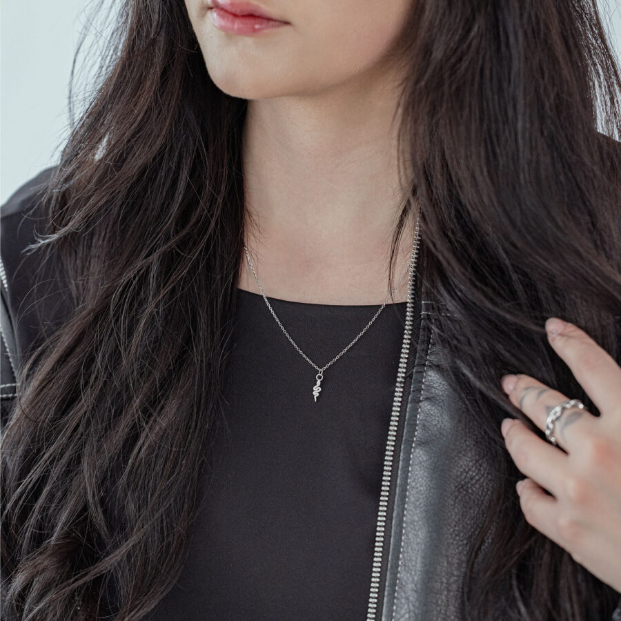 Mujer con cabello largo y oscuro lleva una cadena Little Snake plateada y una chaqueta de cuero negra