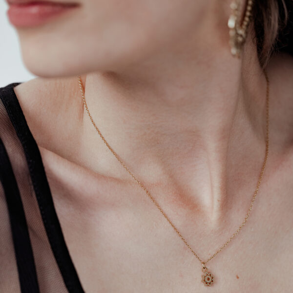 Mujer con collar dorado Little Sunflower, delicado y elegante, sobre fondo claro