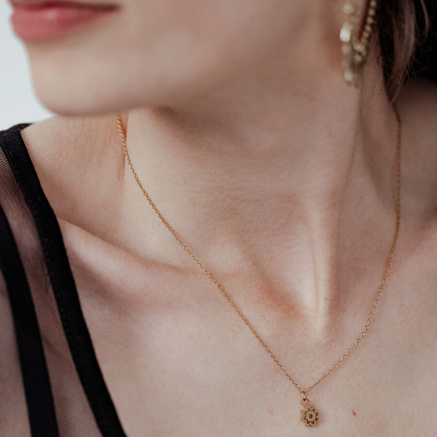Mujer con collar dorado Little Sunflower, delicado y elegante, sobre fondo claro