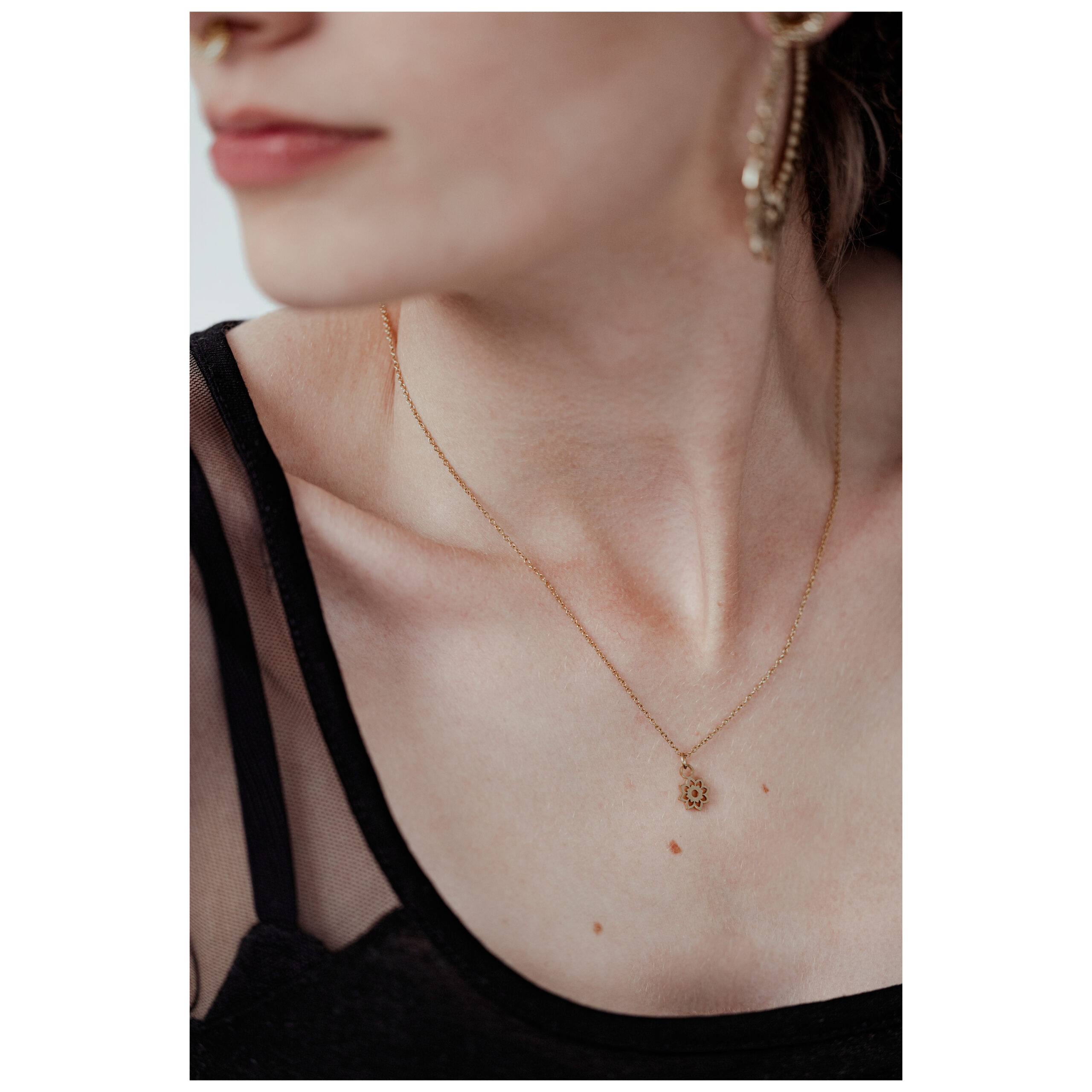 Goldene Little Sunflower Kette auf dem Hals einer Person vor neutralem Hintergrund