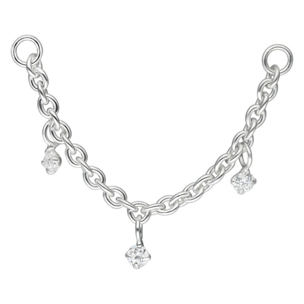 Cadena de piercing plateada con tres colgantes de cristal claro sobre fondo blanco