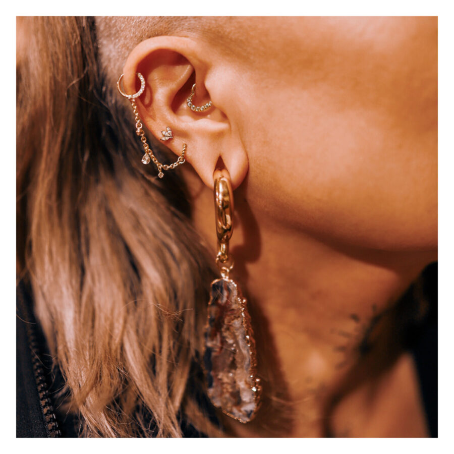 Oreja con cadena de piercing dorada y gota de cristal, vista detallada