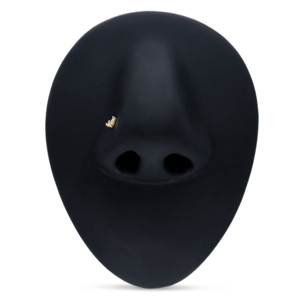 Piercing de nariz dorado en 18K con cristal claro sobre fondo negro
