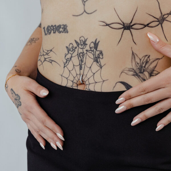 Ombligo con clicker de cristal negro y tatuajes en piel clara