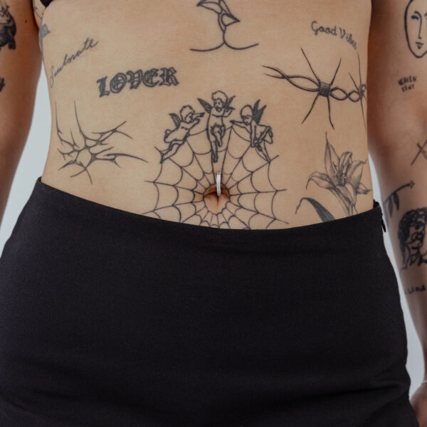 Clicker para ombligo de titanio negro con cristal claro sobre piel con tatuajes