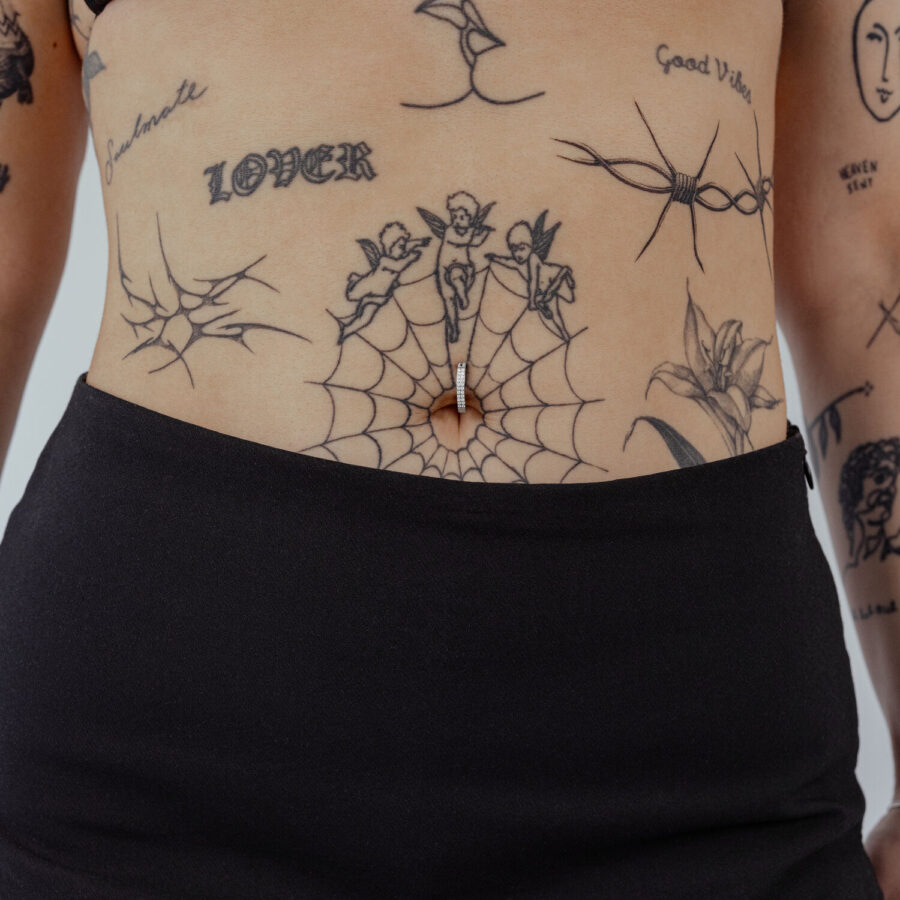 Clicker para ombligo de titanio negro con cristal claro sobre piel con tatuajes