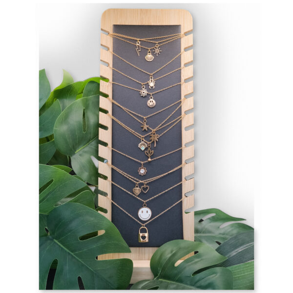 Expositor negro de cuero sintético y madera con collares y plantas al fondo