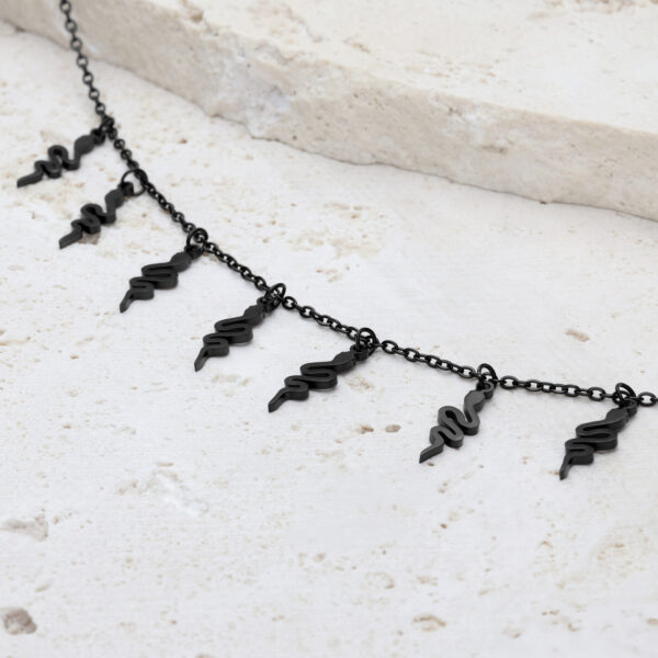 Pulsera Snake negra con cierre ajustable sobre piedra clara