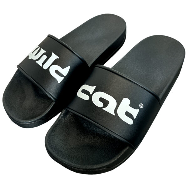 Slides de PVC negras con logo Wildcat blanco sobre fondo neutro