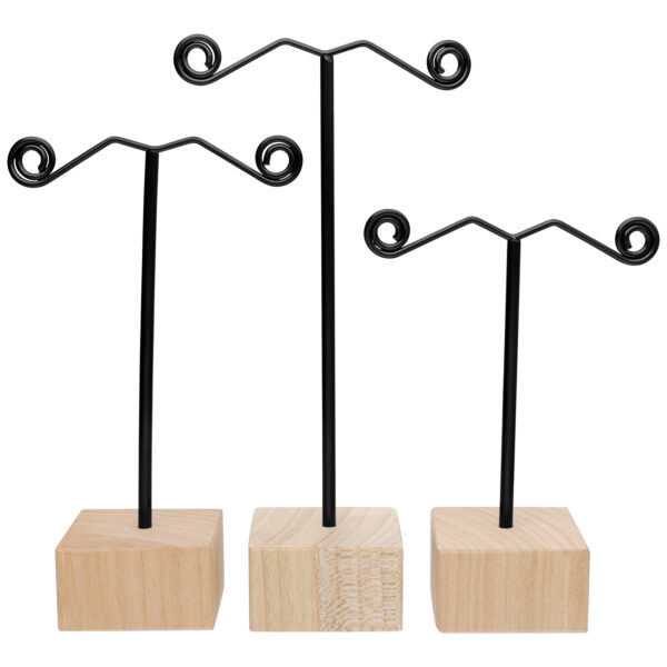 Tres soportes negros para pendientes con base de madera natural sobre fondo blanco