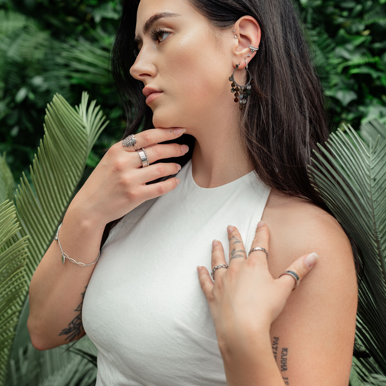 Mujer lleva pendientes de metal negro con chapas sobre fondo verde