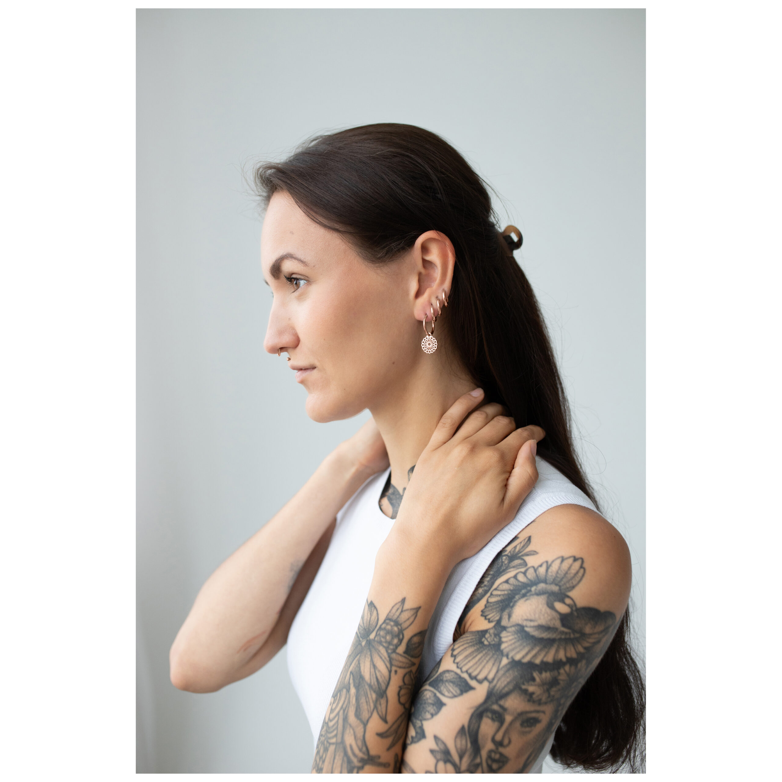 Frau mit langen Haaren trägt roségoldene Mandala Ohrringe, seitliches Profil auf hellem Hintergrund