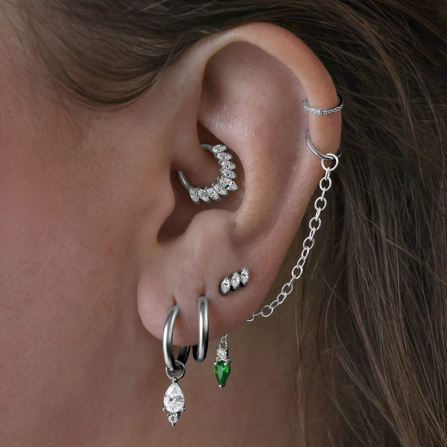 Cadena de piercing de cristal esmeralda llevada en la oreja, conectada con cadena de plata