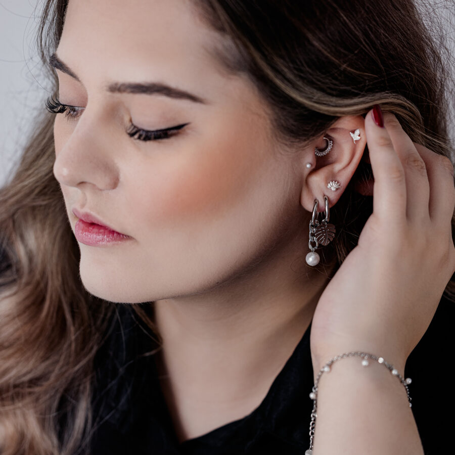Mujer con elegantes aros Chunky de perlas negras y plateadas y otros piercings de oreja