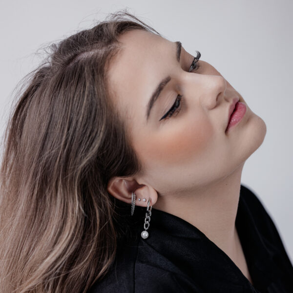 Mujer con piercing Clicker de Triple Cadena con Cristal en la oreja, sobre fondo blanco