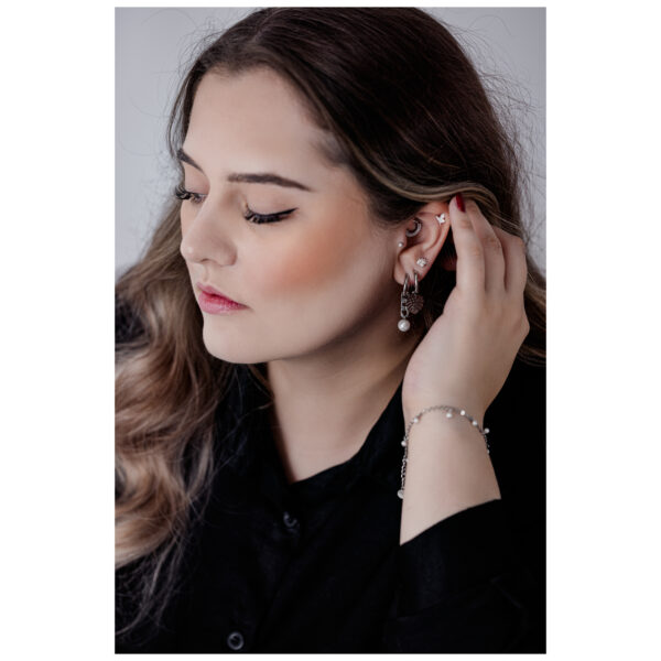 Mujer con cabello largo lleva una pulsera negra y plateada y pendientes