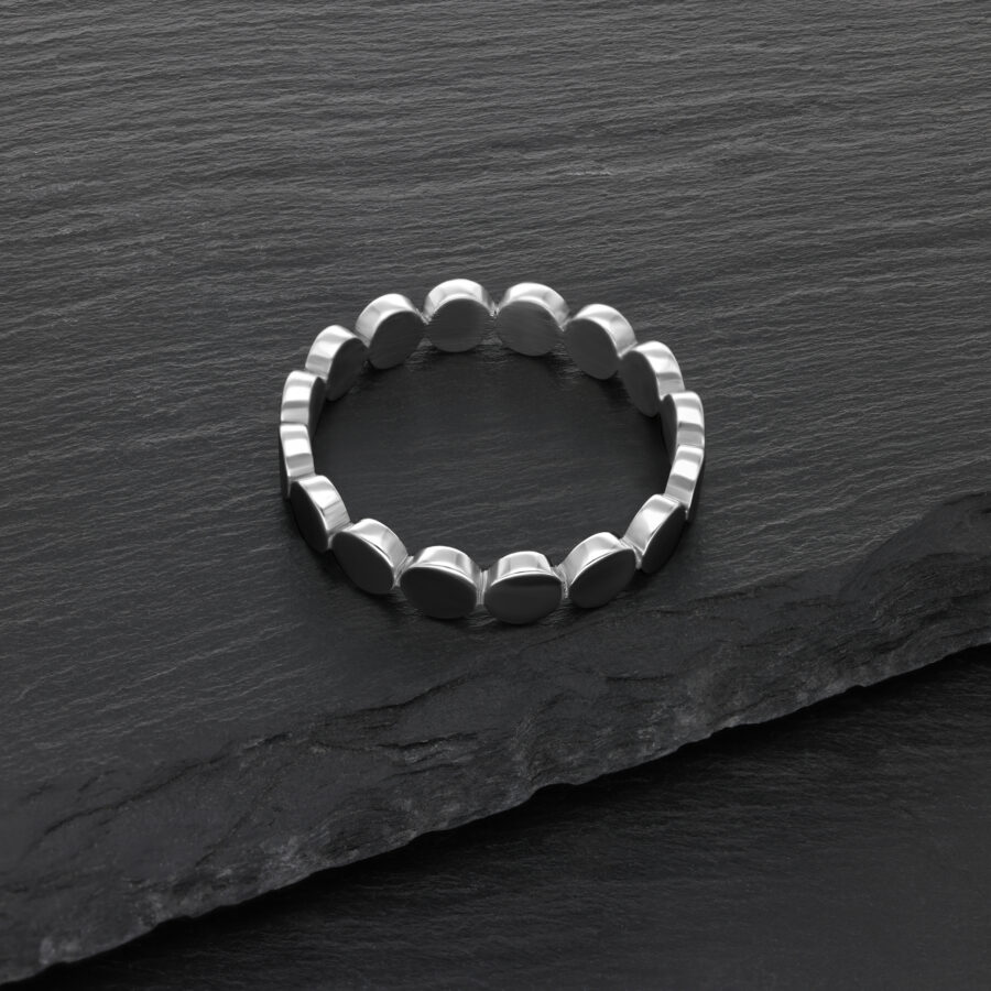Anillo de placa plateado de acero quirúrgico sobre fondo de pizarra negra