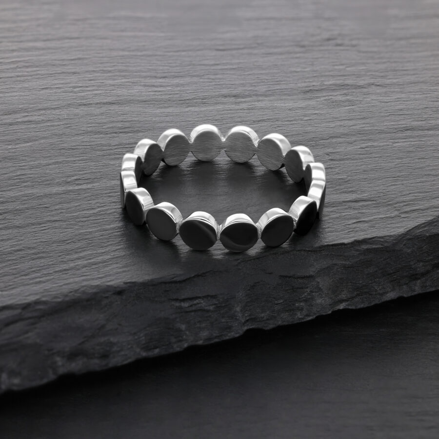 Anillo plateado de acero quirúrgico sobre superficie de piedra oscura