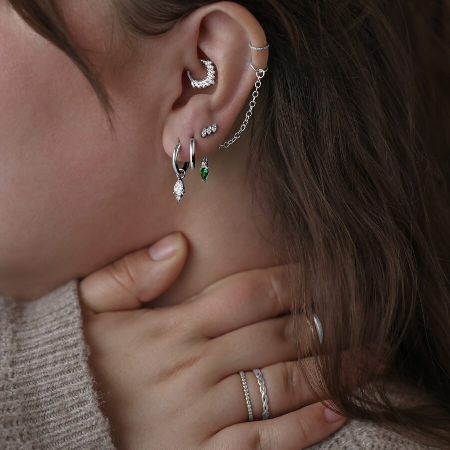 Mujer con varios piercings plateados en la oreja, incluyendo un accesorio Gracia