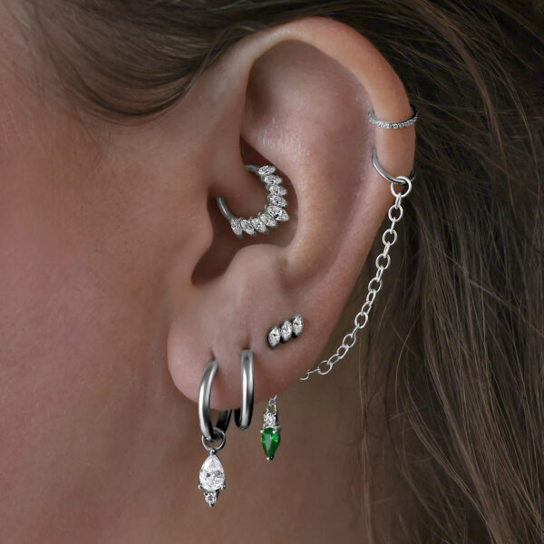 Accesorio de piercing plateado de titanio en la oreja con varios pendientes y cadena