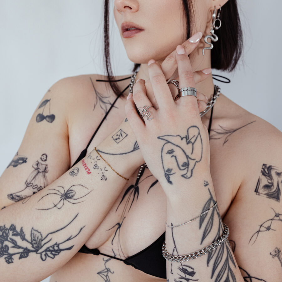 Mujer con brazos tatuados que lleva una pulsera trenzada de plata