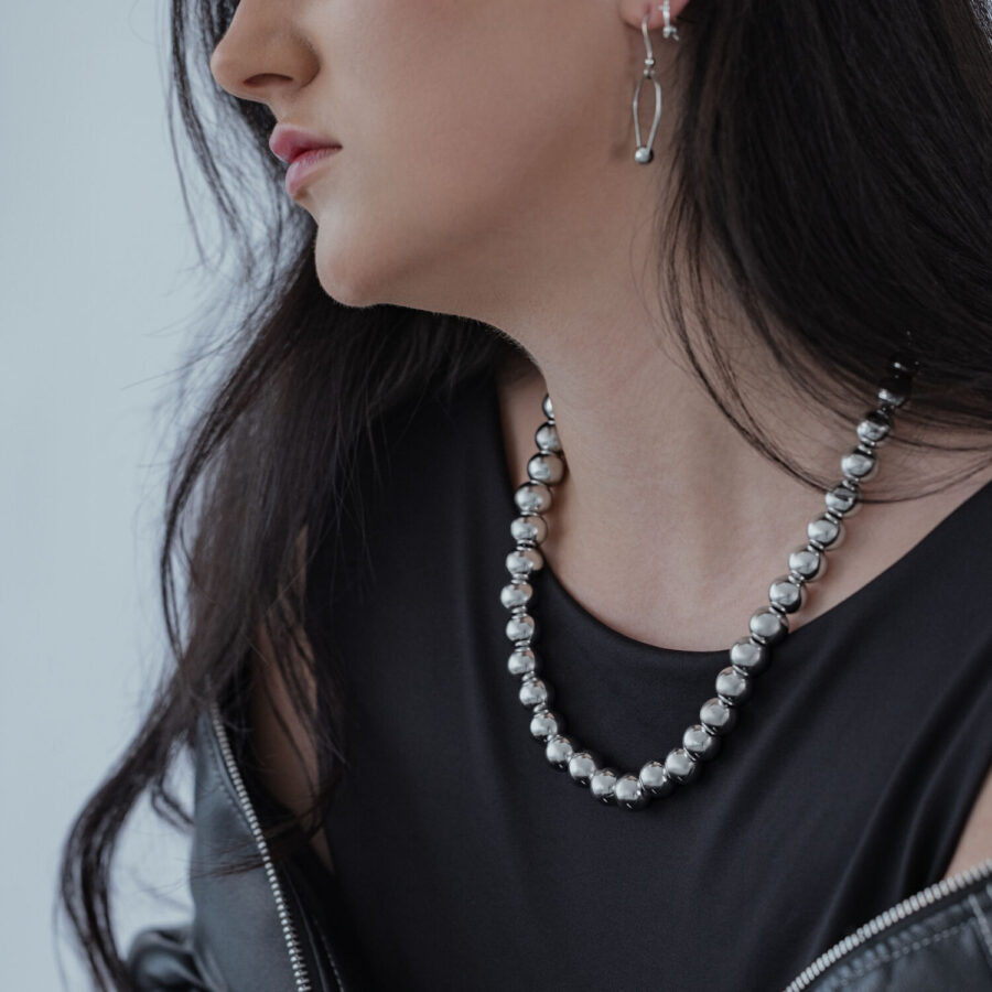 Mujer lleva collar de burbujas plateado de acero quirúrgico con top negro