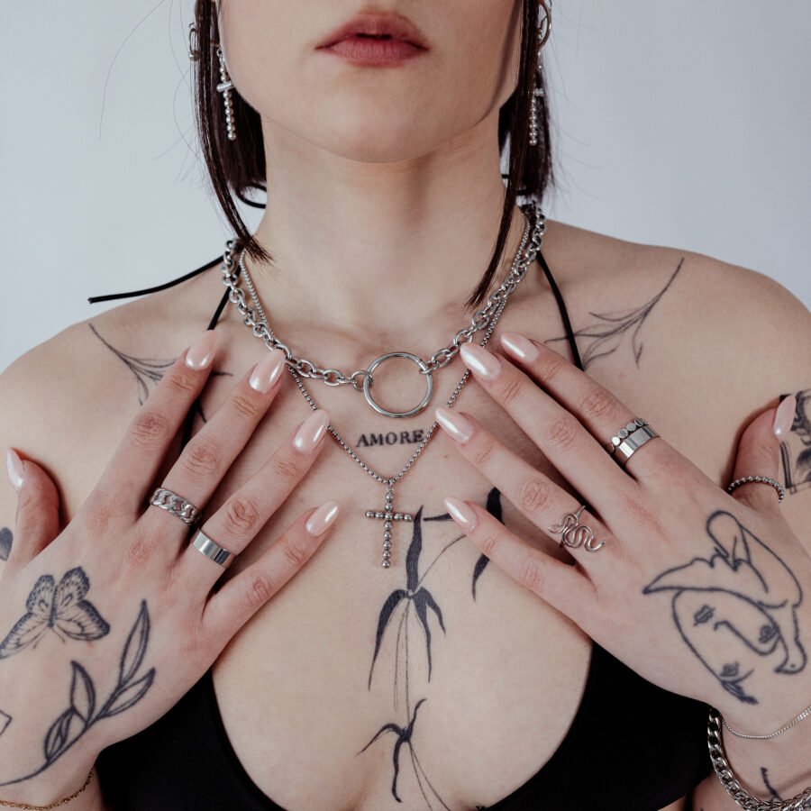 Mujer con Collar Wildcat O de acero quirúrgico, tatuajes y anillos