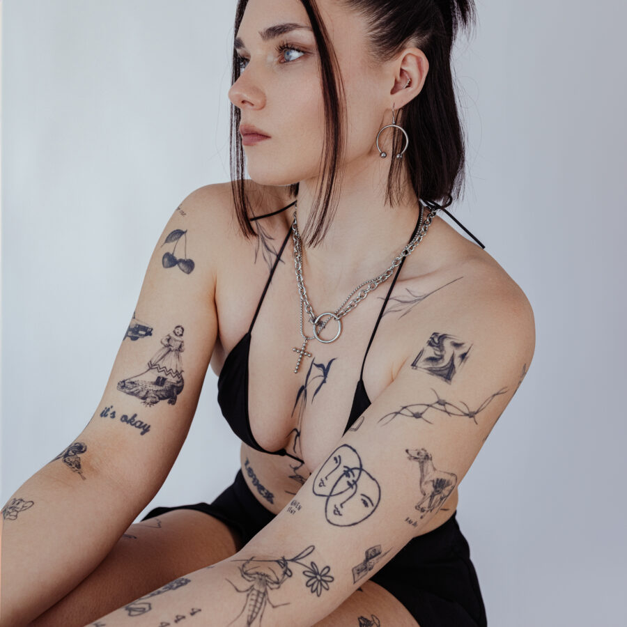 Mujer con collar dorado en O de acero quirúrgico, tatuajes visibles