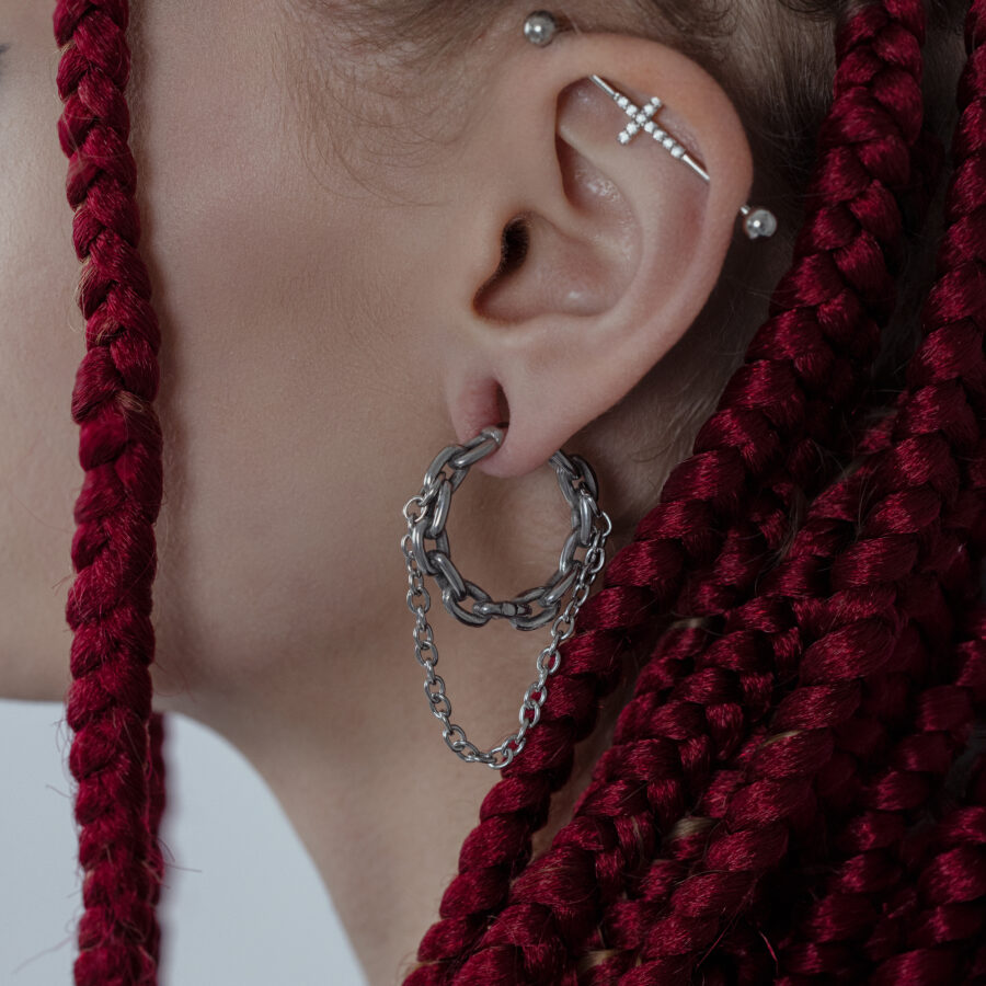 Peso para oreja de cadena doble en plata en una oreja con trenzas rojas