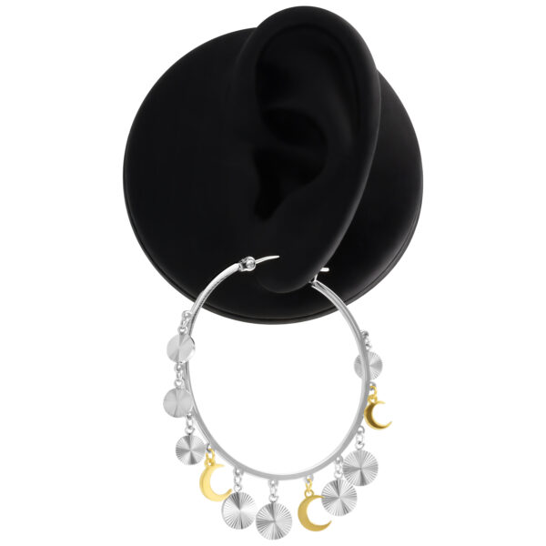 Pendientes colgantes de plata y oro en un expositor negro
