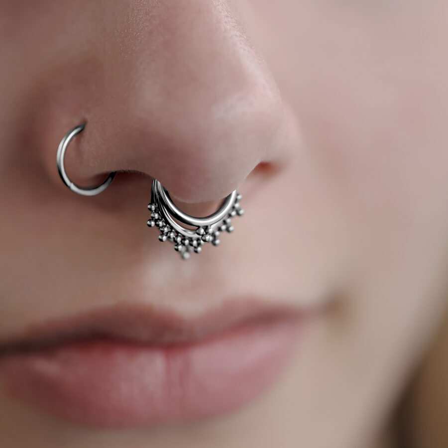 Primer plano de un Triple Oriental Clicker plateado en el septum de una cara