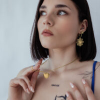 Cadena básica grabable en oro con colgante de corazón Mujer lleva cadena de oro con colgante de corazón, fondo neutro