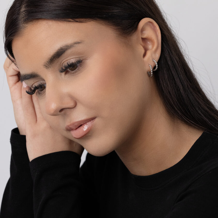 Mujer con pendientes Bubble Hoops negros de acero inoxidable sobre fondo claro
