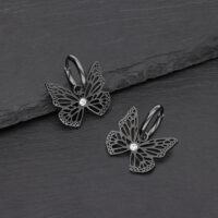 Pendientes de mariposa negros de acero quirúrgico con cristal claro sobre fondo gris