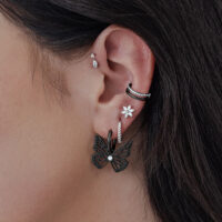 Aros negros en forma de mariposa en una oreja, primer plano de la piel