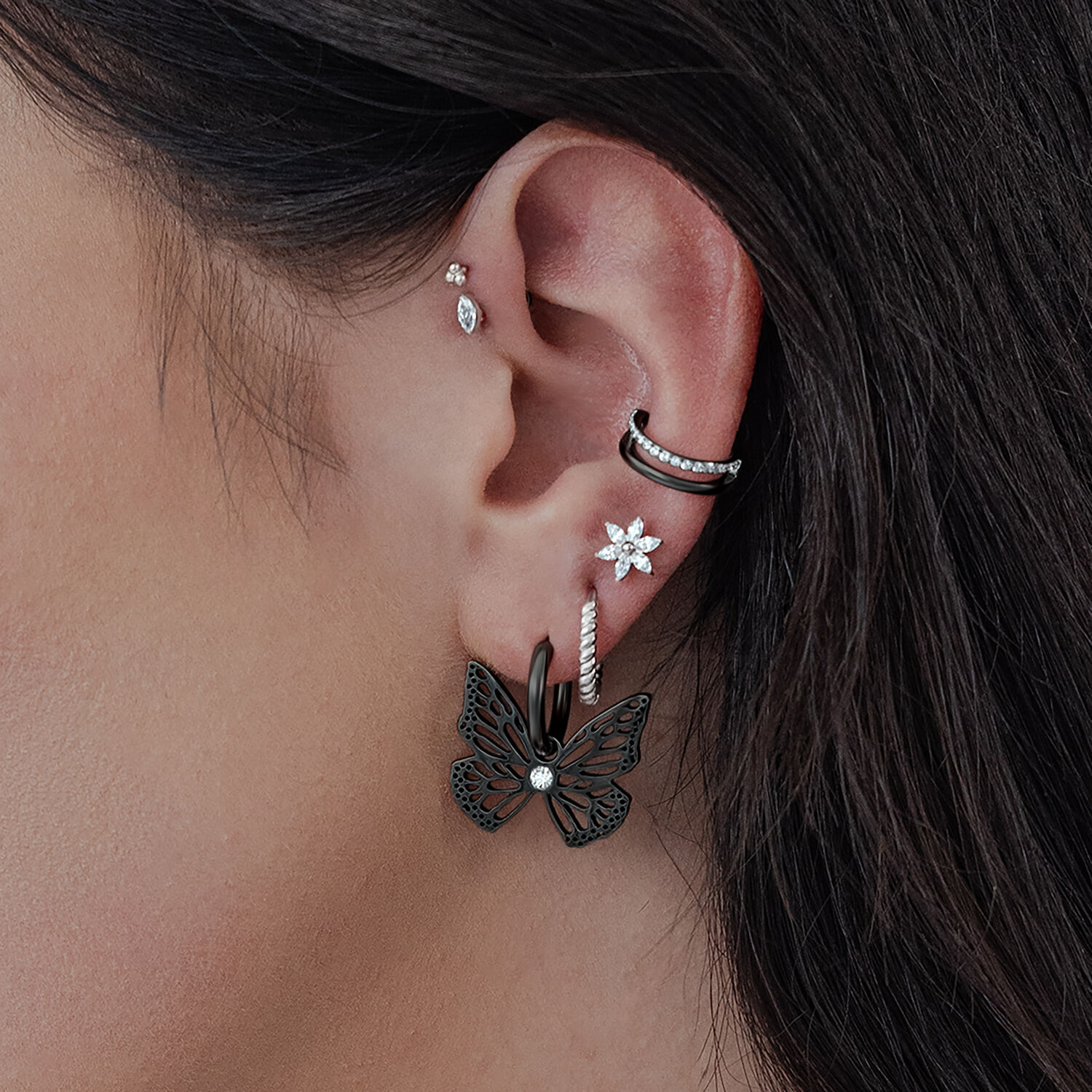Aros negros en forma de mariposa en una oreja, primer plano de la piel