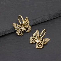 Pendientes de mariposa dorados de metal con cristal claro sobre fondo oscuro