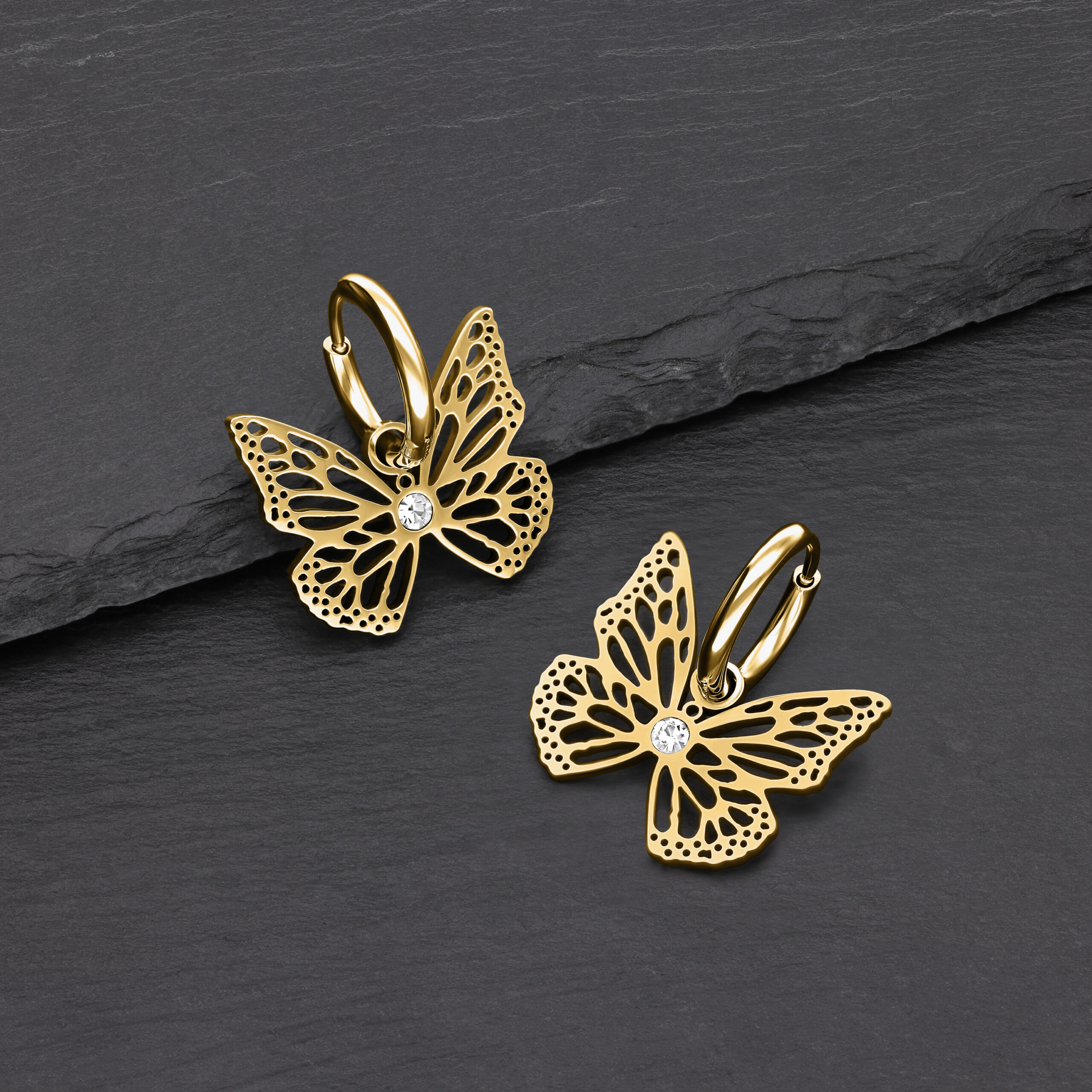 Pendientes de mariposa dorados de metal con cristal claro sobre fondo oscuro