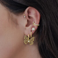 Mujer lleva aros dorados Little Butterfly en la oreja.