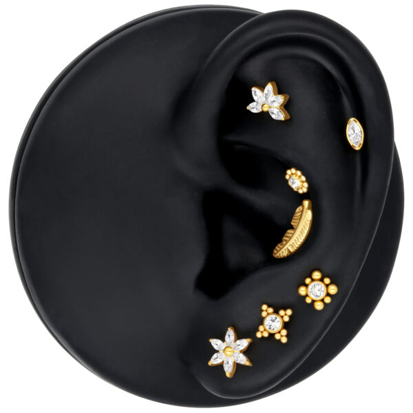 Accesorio con forma de hibisco en plata y oro sobre modelo de oreja negra