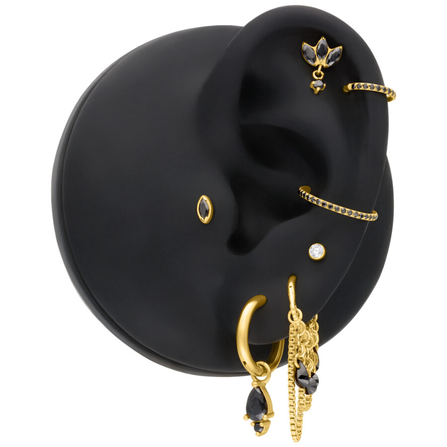 Pieza de piercing dorada con cristal negro diamante en modelo de oreja negra