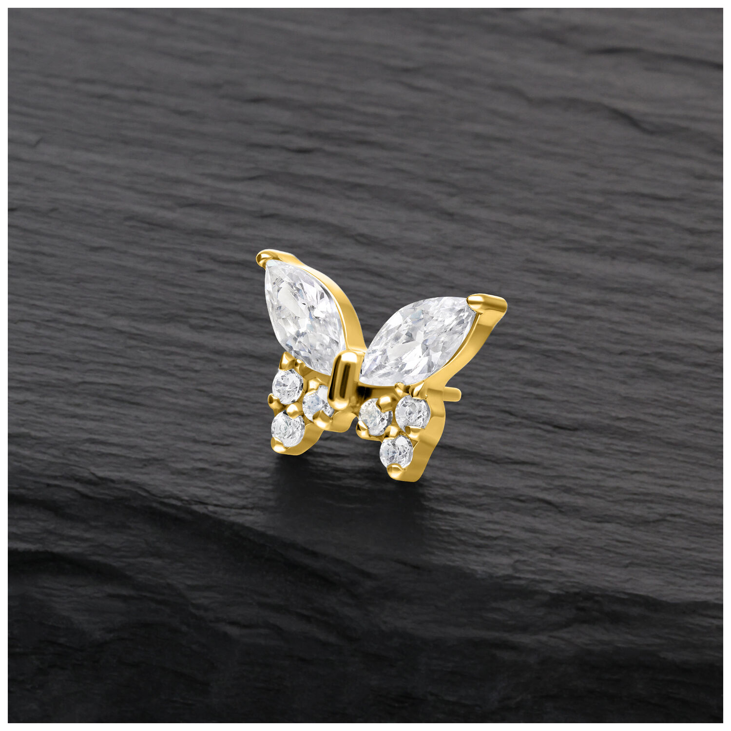 Aro de mariposa dorado con cristales claros sobre fondo negro