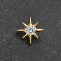 Ajuste metálico dorado en forma de estrella con cristal claro sobre fondo gris