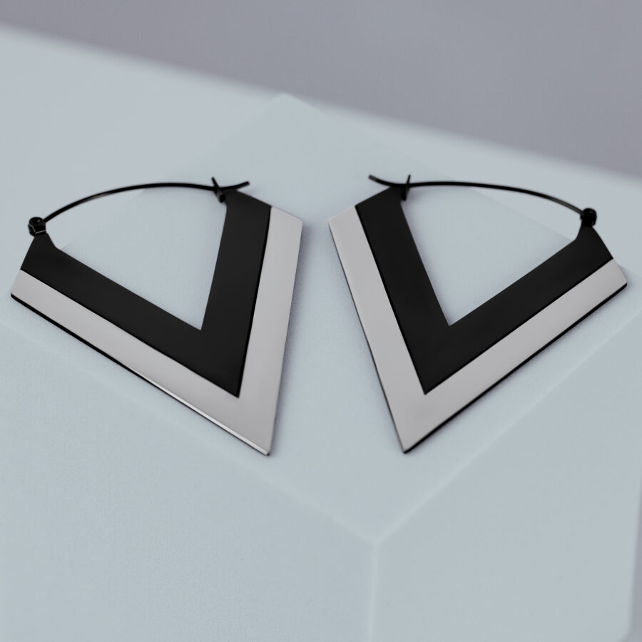 Pendientes en forma de V plateados y negros sobre fondo gris