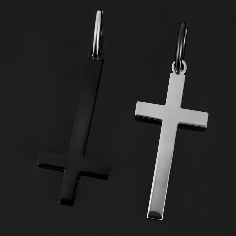Dos pendientes de cruz, uno en negro brillante y otro en plata, sobre fondo negro
