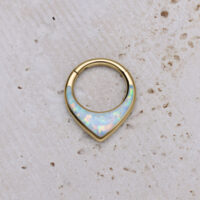 Clicker de septum dorado con ópalo sintético sobre fondo claro