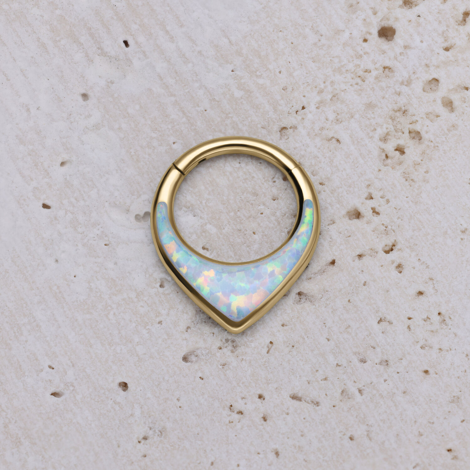 Clicker de septum dorado con ópalo sintético sobre fondo claro